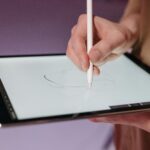 Hand using stylus pen on a tablet for sketching, showcasing modern digital design tools.
